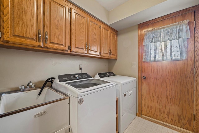 clothes washing area featuring a sink, cabinet space, light floors, and washing machine and dryer