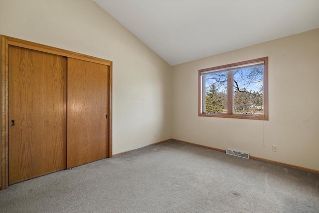 unfurnished bedroom with visible vents, light colored carpet, baseboards, and lofted ceiling