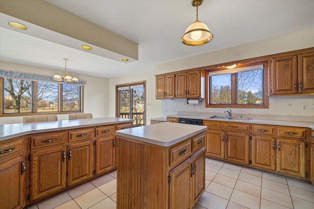 kitchen featuring brown cabinets, a center island, light countertops, and a sink