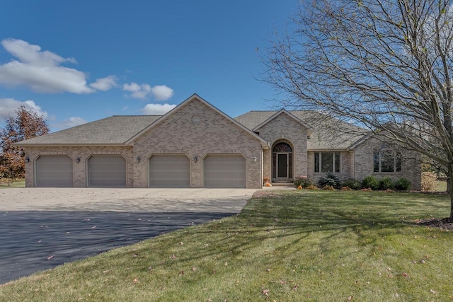 french country home with aphalt driveway, a front yard, a shingled roof, a garage, and brick siding