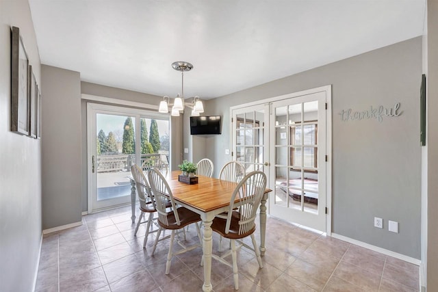 dining space featuring light tile patterned floors, french doors, baseboards, and a notable chandelier