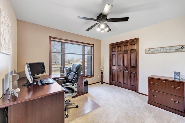 home office featuring a ceiling fan, light colored carpet, and baseboards