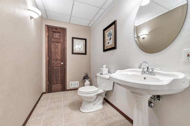 bathroom featuring tile patterned flooring, visible vents, baseboards, a drop ceiling, and toilet