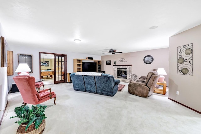 carpeted living room featuring a brick fireplace, baseboards, and ceiling fan