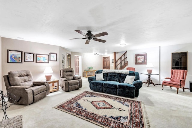 carpeted living area featuring stairway and a ceiling fan