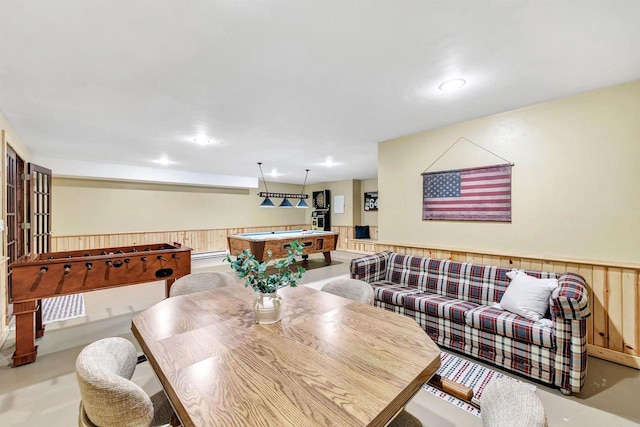 dining space featuring wooden walls, wainscoting, pool table, and concrete flooring