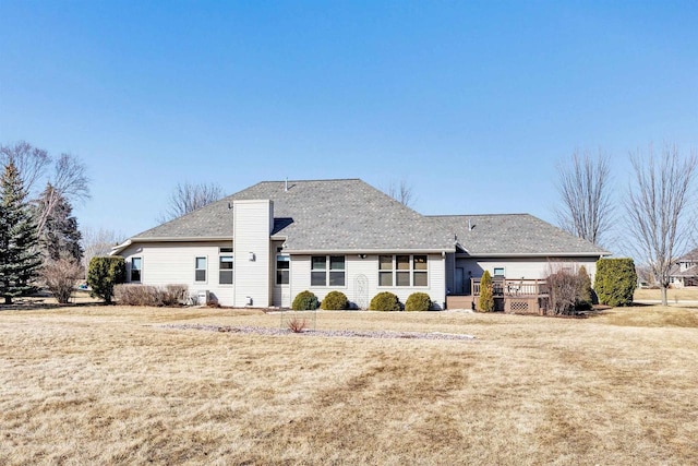 rear view of property featuring a wooden deck, a lawn, and a shingled roof