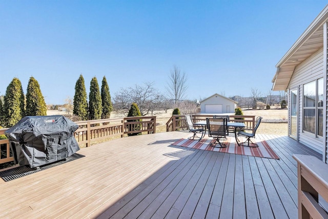 deck featuring an outbuilding, a detached garage, a grill, and outdoor dining area