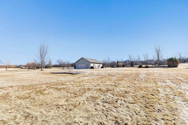 view of yard featuring an outbuilding, a rural view, and a detached garage