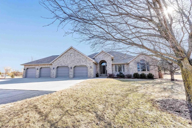 french country home featuring an attached garage, a shingled roof, a front lawn, aphalt driveway, and brick siding