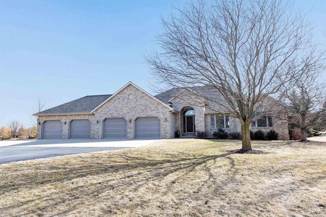 french country style house featuring a front lawn, concrete driveway, an attached garage, a shingled roof, and brick siding