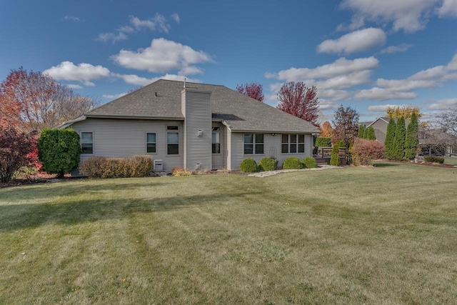 rear view of house with a shingled roof, a lawn, and a chimney