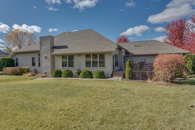 back of property featuring a shingled roof, a yard, a chimney, and a wooden deck