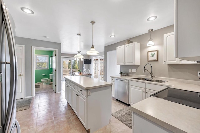 kitchen with white cabinets, a kitchen island, appliances with stainless steel finishes, and a sink