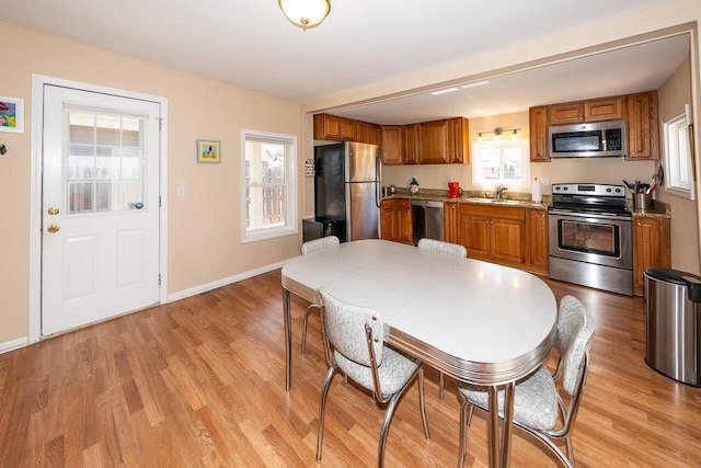 kitchen with a sink, brown cabinetry, and stainless steel appliances