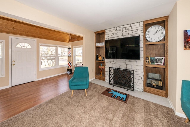 interior space with beam ceiling, a fireplace, baseboards, and wood finished floors