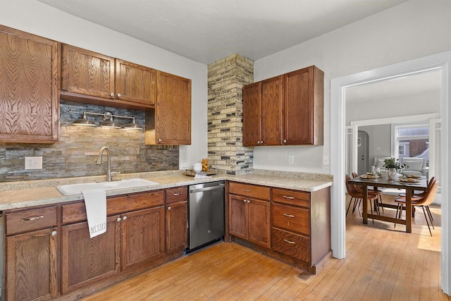 kitchen featuring stainless steel dishwasher, light countertops, light wood-style flooring, and backsplash