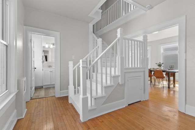 stairs featuring decorative columns, baseboards, and wood-type flooring