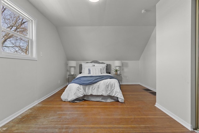 bedroom featuring baseboards, wood-type flooring, and lofted ceiling