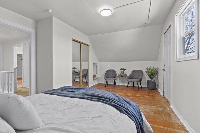 bedroom featuring lofted ceiling, wood finished floors, and baseboards