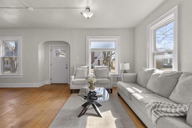 living area featuring baseboards, arched walkways, and wood finished floors