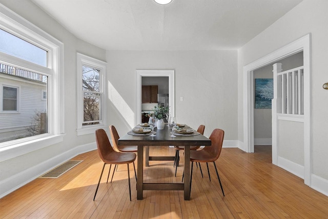 dining room with baseboards, visible vents, and light wood finished floors