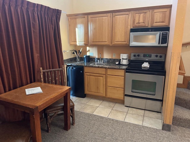 kitchen with a sink, stainless steel appliances, light colored carpet, and light tile patterned floors