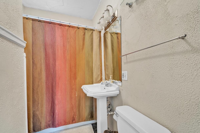 full bathroom featuring toilet and a textured wall