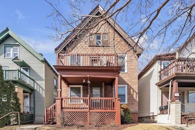 view of front of house with a porch, a balcony, and brick siding