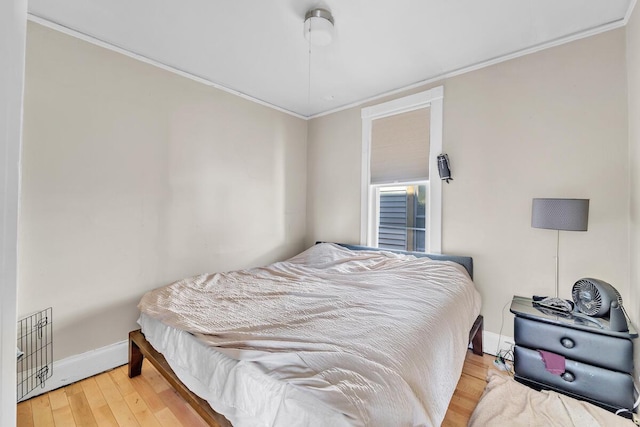 bedroom with baseboards, wood finished floors, and crown molding