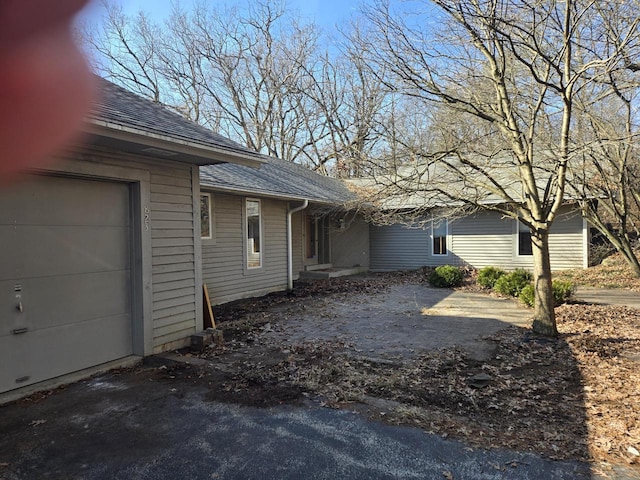 view of home's exterior with a garage and roof with shingles