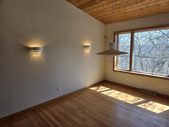 spare room featuring wood finished floors, visible vents, baseboards, lofted ceiling, and wood ceiling