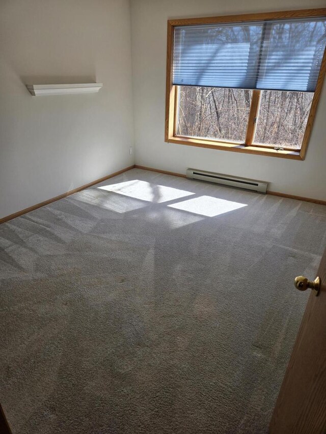 carpeted spare room with a baseboard radiator and baseboards