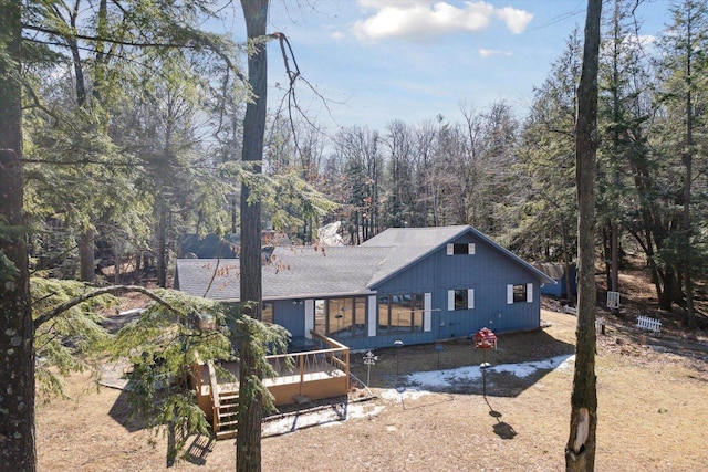 rear view of property with a wooden deck and a shingled roof