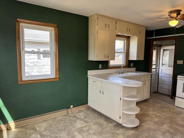 kitchen with a sink, a baseboard heating unit, open shelves, light countertops, and baseboards