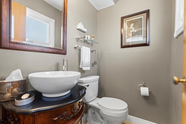 bathroom with baseboards, toilet, and vanity