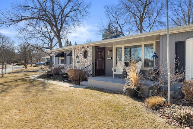 view of front facade featuring a front lawn, a porch, and stone siding