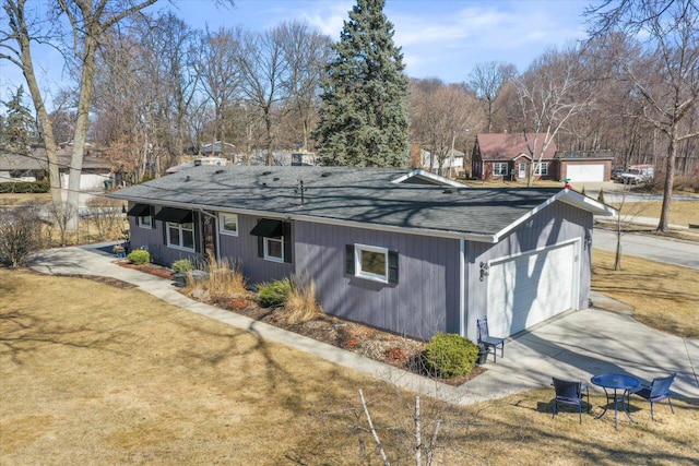 exterior space featuring a detached garage, a lawn, and a shingled roof