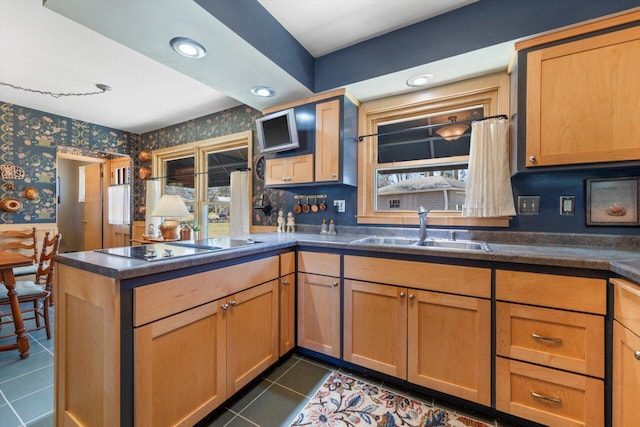 kitchen featuring wallpapered walls, a peninsula, plenty of natural light, black electric cooktop, and a sink