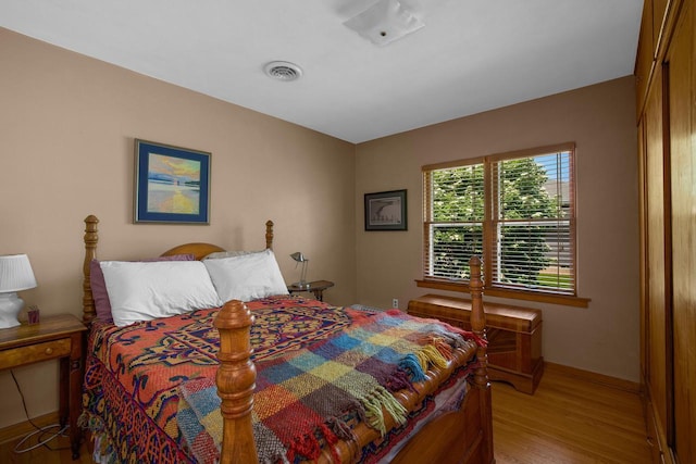 bedroom with light wood-style floors and visible vents