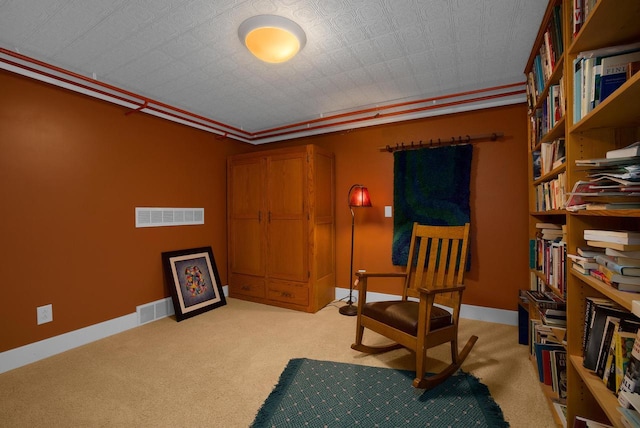 sitting room featuring light carpet, visible vents, baseboards, and ornamental molding