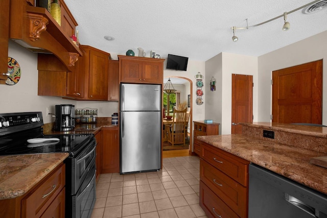 kitchen featuring brown cabinetry, visible vents, range with two ovens, freestanding refrigerator, and dishwasher