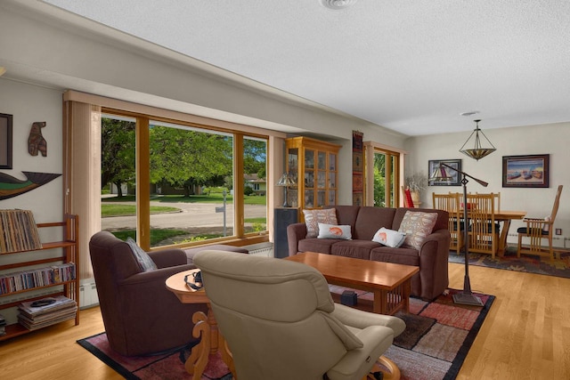 living room with a baseboard heating unit, a textured ceiling, and light wood-style flooring