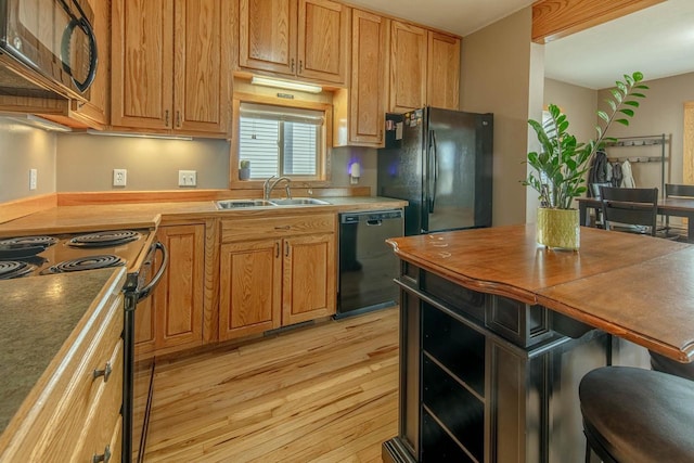 kitchen featuring butcher block counters, black appliances, light wood-style floors, and a sink