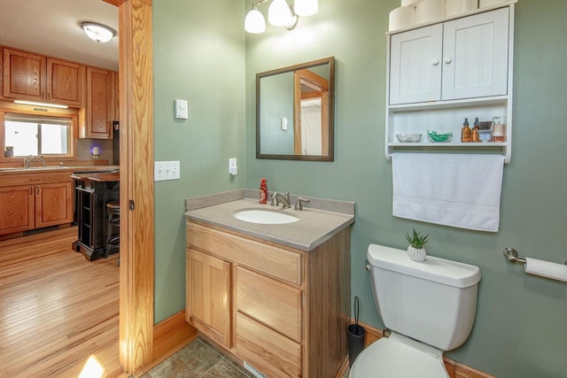 bathroom featuring toilet, vanity, and baseboards