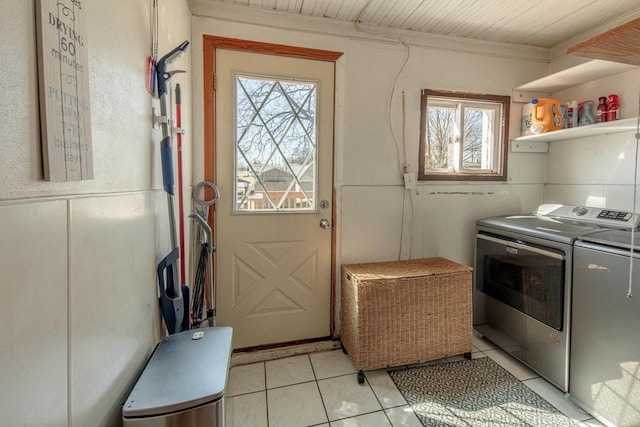 clothes washing area with light tile patterned floors, laundry area, washer and dryer, and crown molding