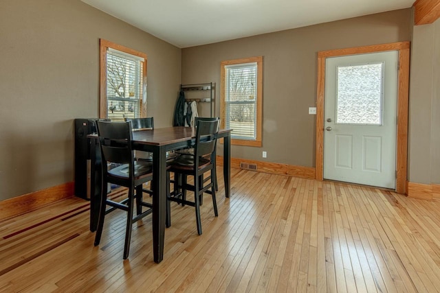 dining space with visible vents, light wood-style flooring, baseboards, and a healthy amount of sunlight