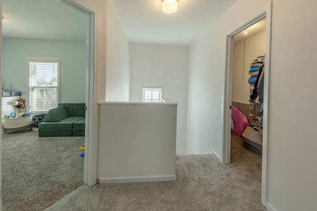 corridor featuring baseboards, an upstairs landing, and carpet