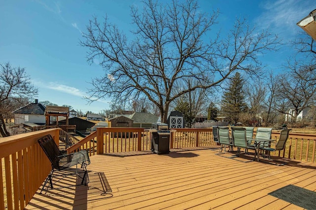 wooden deck with an outbuilding, a grill, and a storage shed