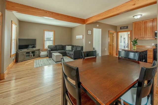 dining room featuring beam ceiling, baseboards, and light wood-style floors